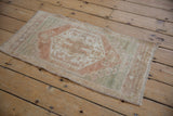 Distressed vintage Oushak rug detail showing faded beige, pale copper, and seafoam patterns.