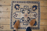 Distressed Oushak square rug exhibiting antique ivory, navy blue, and blush floral patterns.