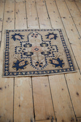 Distressed vintage Oushak rug corner showing navy blue vine border and palmette motifs.