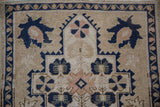 Distressed Oushak rug's ivory field features navy blue palmettes and soft pink floral motifs.