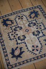 Distressed vintage Oushak rug corner with navy blue vine border and softened ivory palmette.