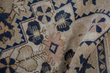 Vintage distressed Oushak rug's pile and navy, beige, pink floral motifs with rolled edge.
