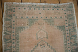 Detail of vintage Oushak rug's worn beige pile, seafoam geometric border, and faint foundation.