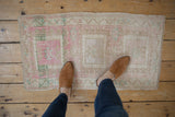 Faded blush and beige geometric patterns on a distressed vintage Oushak rug mat.