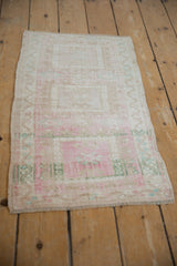 Distressed Oushak rug mat section with muted geometric blossoms and soft pink, ivory tones.