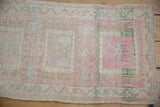 Distressed vintage Oushak rug's side selvage with pink, beige, and green geometric motifs.