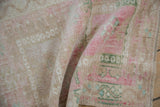 Distressed vintage Oushak rug's folded pile, showing even wear and pink, beige geometric blossoms.
