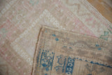 Corner of distressed Oushak rug showing worn pile and hand-knotted reverse with blue geometric pattern.