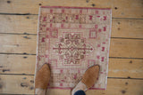 Distressed vintage Oushak mat featuring pale raspberry red geometric spandrel and even wear.