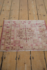 Distressed corner of a vintage Oushak rug, showing geometric spandrel in raspberry and ivory.