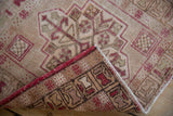 Distressed Oushak rug pile with raspberry geometric pattern, curled back to reveal hand-knotted reverse.