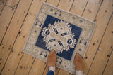 Distressed Oushak rug corner, showing blue serrated pattern, abrashed ground, and intact selvage.