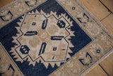 Distressed Oushak rug with dark blue serrated border and faded beige ground texture.