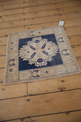 Distressed Oushak rug corner detail showing low pile, navy, and beige geometric patterns.