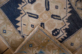 Corner of distressed Oushak rug showing faded navy geometric design on neutral ground and woven foundation.