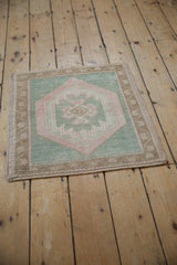 Distressed Oushak rug corner with meandering vine border and seafoam green field.