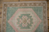 Distressed seafoam green Oushak rug with pale blush and bronze decorative border.