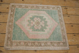 Distressed Oushak rug corner: seafoam green, pale blush geometric pattern, and bronze border.