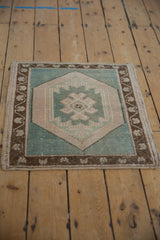 Distressed Oushak rug corner with deep bronze meandering vine border, seafoam accents.