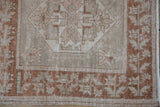 Detailed distressed copper border with germinating plant motif on a vintage Oushak rug.