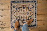 Distressed vintage Oushak rug showcasing worn pile and beige, navy floral motifs.