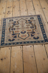 Distressed Oushak rug detail: beige shield medallion, navy blossoms, coffee brown motifs, with even wear.