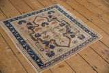Distressed Oushak rug's navy vine border, faded floral field, with visible foundation wear.