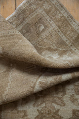 Textured fold of distressed vintage Oushak rug, showing even pile wear, beige and ivory shades.