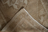 Distressed pile of vintage Oushak rug, revealing its woven back and beige side selvage.