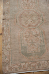 Distressed Oushak rug, showing soft pile texture and faded geometric patterns in beige and seafoam.