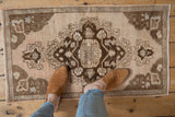 Decorative distressed Turkish Oushak mat with ornate brown and ivory medallion.