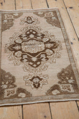 Vintage distressed Oushak mat with abrashed ivory field and faded chocolate medallion.