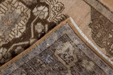 Distressed Oushak rug corner shows short brown pile, intact selvage, and hand-knotted back.