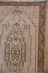Distressed Oushak rug with short pile, beige stepped field, and copper floral border.