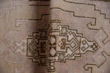 Distressed pile texture and muted geometric patterns on this vintage Oushak rug's fold.