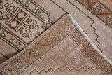 Distressed Oushak rug corner revealing woven back, intact selvage, geometric pattern.