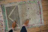Vintage Distressed Oushak rug with heavy abrashes and neutral colors, accented by pink and emerald green.