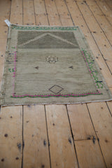 Distressed Oushak rug left side: silver tones, emerald green, pink meandering border.