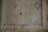 Oushak rug corner with textured silver field, vivid pink and emerald green border, fringe.