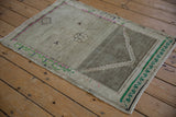 Distressed vintage Oushak rug corner showing emerald green meandering vine border.