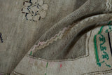 Folded vintage distressed Oushak rug showing tonal abrashes, pink, and emerald green patterns.