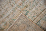 Distressed ivory, seafoam, brown Oushak pile with exposed knot heads and intact selvage.