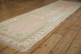 Distressed Oushak rug runner side with dusty rose, ivory, and beige floral border.