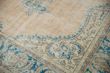 Distressed vintage Oushak carpet corner with sky blue vinery and worn beige pile texture.