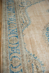 Distressed vintage Oushak rug with worn beige field, faint foundation visible, and blue border.