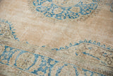 Distressed beige and ivory pile of Oushak rug, showing faint foundation and blue motifs.