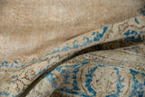 Distressed Oushak rug pile revealing faded sky blue motifs on a beige and ivory ground.