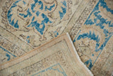 Distressed Oushak carpet's worn beige and blue pile with woven foundation and intact selvage.