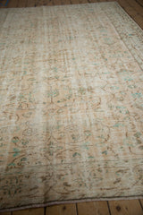 Distressed ivory Oushak carpet with pale turquoise and coffee brown scrolling floral pattern.