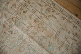 Distressed Oushak carpet pile showing worn texture, beige, and pale turquoise vinery, with side selvage.